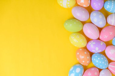 Mutlu Paskalya bayramı kutlamaları. Sarı arka planda renkli yumurta süsleme grubu. Mevsimsel din geleneği tasarımı. Üst görünüm, kopyalama alanı, düz uzanma.