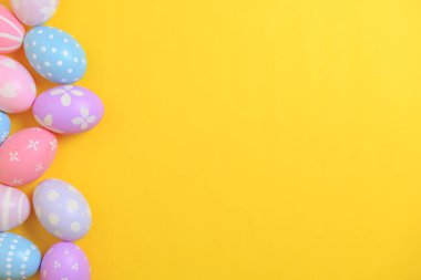 Mutlu Paskalya bayramı kutlamaları. Sarı arka planda renkli yumurta süsleme grubu. Mevsimsel din geleneği tasarımı. Üst görünüm, kopyalama alanı, düz uzanma.