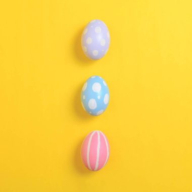 Mutlu Paskalya bayramı kutlamaları. Sarı arka planda renkli yumurta süsleme grubu. Mevsimsel din geleneği tasarımı. Üst görünüm, kopyalama alanı, düz uzanma.