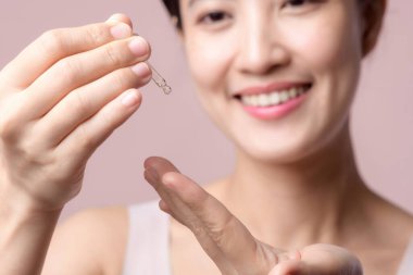 Genç ve güzel Asyalı bir kadın yüz derisine serum yüz yağı sürüyor. Sağlık portresi, temiz cilt bakımı, çekici kadın ve tedavi düşürücü. Güzellik, kozmetoloji konsepti