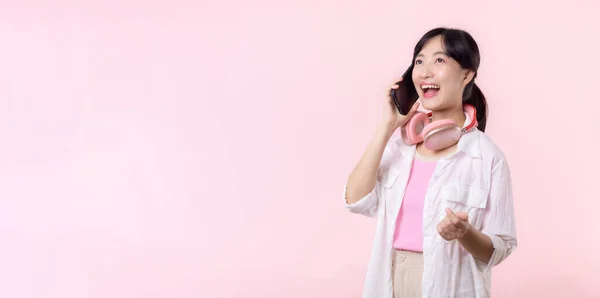 매력적 아시아 분홍색 스튜디오 배경에 스마트폰 헤드폰을 사용하여 미소를 전화를 — 스톡 사진