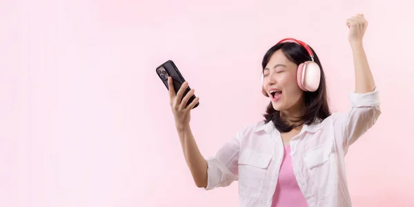 笑顔の若いアジアの女性が目を閉じて スマートフォンでリラックスして踊り ワイヤレスヘッドフォンで音楽を聴いてください 人々の感情 ライフスタイルのレジャーや美しさの概念 — ストック写真