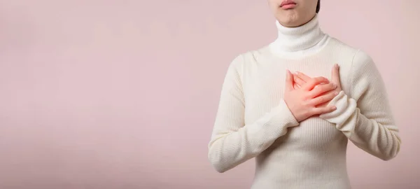 薄いピンク色のスタジオの背景に心臓発作で苦しんでいる若いアジアの女性 痛みを伴うけいれん 心臓病 痛みを伴う式で胸を押す 医療の概念 — ストック写真