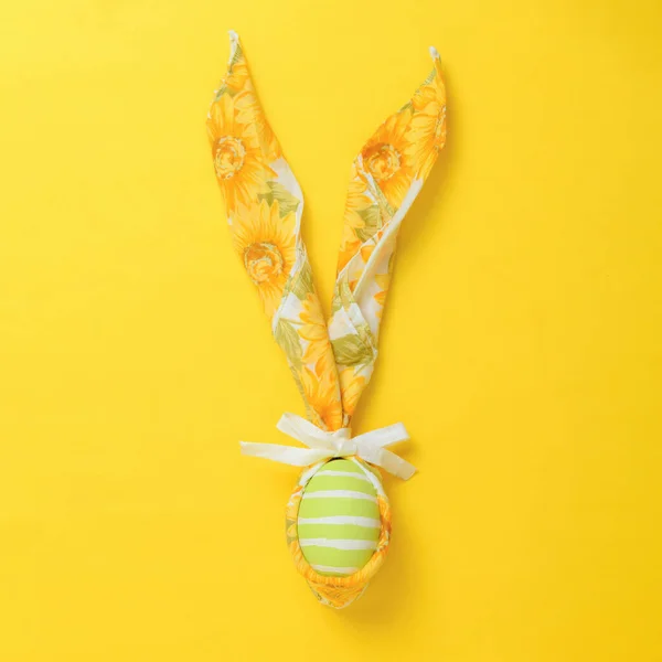 stock image Painted green easter egg decorated with a napkin in the shape of a bunny on yellow background