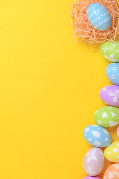 幸せなイースターお祝いの休日 カラフルなパステルは黄色の背景にウィッカーバスケット巣の装飾で卵を描いた 季節のグリーティングギフトカードコンセプト フラットレイアウト トップビュー コピースペース — ストック写真