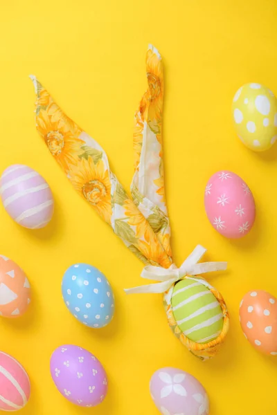 色彩艳丽的彩绘复活节彩蛋 用黄色背景的兔子形餐巾装饰 — 图库照片