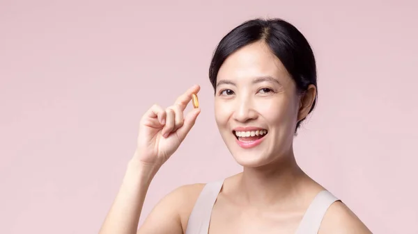 若い肖像画アジアの女性ビタミン栄養薬で幸せな笑顔の顔 ピンクの背景に隔離されたかなりかわいい女の子の女性の人健康カプセルサプリメントスキンケアを保持 薬の概念 — ストック写真