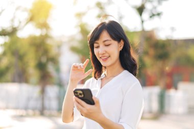 Portrait beautiful young asian woman with smart mobile phone around outdoor nature view in sunny summer day