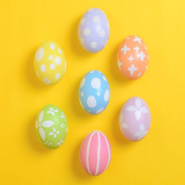 Mutlu Paskalya bayramı kutlamaları. Sarı arka planda renkli yumurta süsleme grubu. Mevsimsel din geleneği tasarımı. Üst görünüm, kopyalama alanı, düz uzanma.