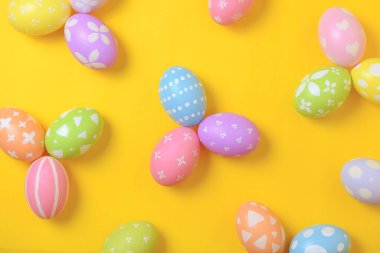 Mutlu Paskalya bayramı kutlamaları. Sarı arka planda renkli yumurta süsleme grubu. Mevsimsel din geleneği tasarımı. Üst görünüm, kopyalama alanı, düz uzanma.