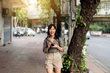 Young Asian woman backpack traveler using digital compact camera, enjoying street cultural local place and smile.