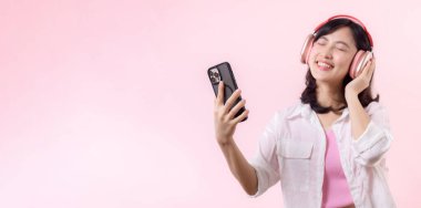 Mutlu gülümseyen Asyalı genç kadın gözlerini kapat ve akıllı telefonla dans et, kablosuz kulaklıkla müzik dinle. Halk duyguları, yaşam tarzı eğlence ve güzellik konsepti.