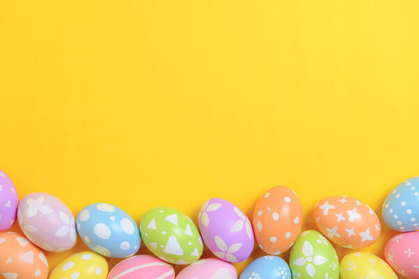 Happy easter holiday celebration concept. Group of painted colourful eggs decoration on a yellow background. Seasonal religion tradition design. Top view, copy space, flat lay.