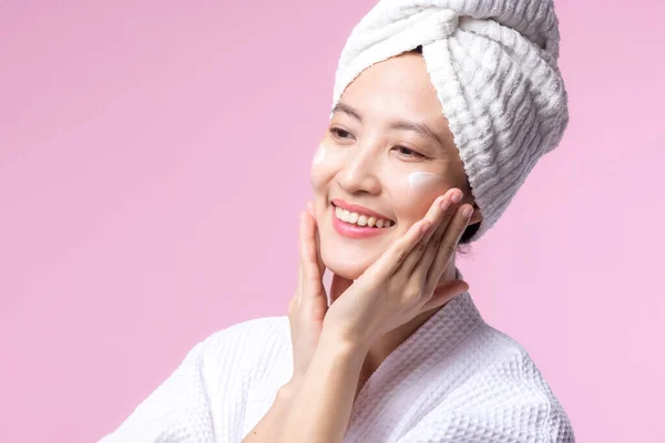 아시아의한 여성은 얼굴에 스킨케어 크림을 바르는데 화장품을 사용하는 피부에 얼굴을 — 스톡 사진