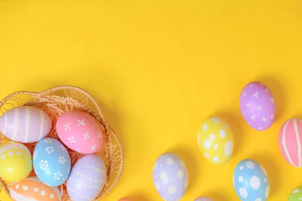 复活节快乐 五颜六色的彩绘彩绘鸡蛋在柳条篮窝装饰黄色背景 季节性贺卡的概念 平面布局 顶视图 复制空间 — 图库照片