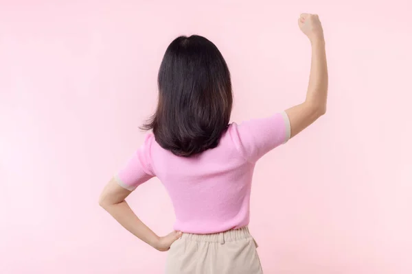 Portrait back of woman proud and confident showing strong muscle strength arms flexed posing, feels about her success achievement. Women empowerment, equality, strength and courage concept