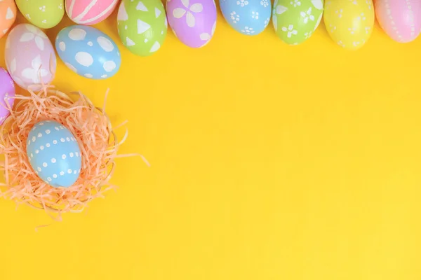 复活节快乐 五颜六色的彩绘彩绘鸡蛋在柳条篮窝装饰黄色背景 季节性贺卡的概念 平面布局 顶视图 复制空间 — 图库照片