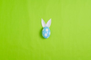 Mutlu Paskalya bayramı tebrik kartı konsepti. Renkli Paskalya yumurtaları ve pastel yeşil arka planda bahar çiçekleri. Üst görünüm, düz görünüm, kopyalama alanı.