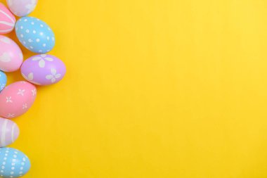 Mutlu Paskalya bayramı kutlamaları. Sarı arka planda renkli yumurta süsleme grubu. Mevsimsel din geleneği tasarımı. Üst görünüm, kopyalama alanı, düz uzanma.