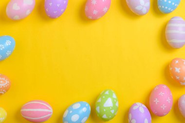 Mutlu Paskalya bayramı kutlamaları. Sarı arka planda renkli yumurta süsleme grubu. Mevsimsel din geleneği tasarımı. Üst görünüm, kopyalama alanı, düz uzanma.