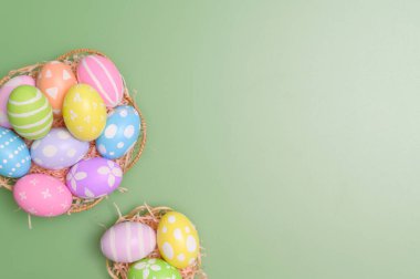 Mutlu Paskalya bayramı tebrik kartı konsepti. Renkli Paskalya yumurtaları ve pastel yeşil arka planda bahar çiçekleri. Üst görünüm, düz görünüm, kopyalama alanı.