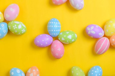 Mutlu Paskalya bayramı kutlamaları. Sarı arka planda renkli yumurta süsleme grubu. Mevsimsel din geleneği tasarımı. Üst görünüm, kopyalama alanı, düz uzanma.