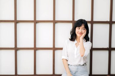 Portrait beautiful young asian woman happiness sitting on wooden grid wall, Happy female is smiling on wooden grid wall