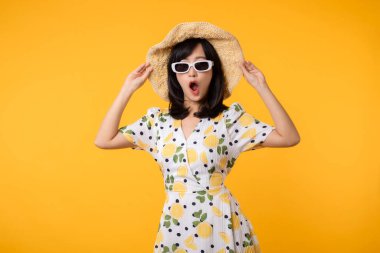 Genç, neşeli Asyalı kadın mutlu bir gülümseme ilkbahar kadın tarzı moda ve sarı arka planda izole edilmiş güneş gözlükleri. Çekici, güzel, manken kız yaz mevsiminde duygu pozu veriyor..
