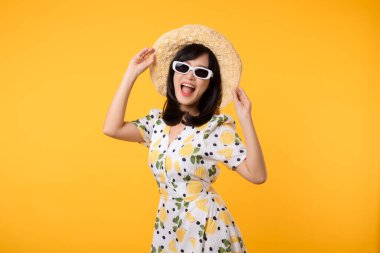 Genç, neşeli Asyalı kadın mutlu bir gülümseme ilkbahar kadın tarzı moda ve sarı arka planda izole edilmiş güneş gözlükleri. Çekici, güzel, manken kız yaz mevsiminde duygu pozu veriyor..