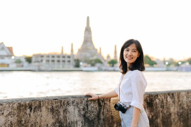 Güzel Asyalı kadının portresi Wat Arun 'da gün batımı manzarasında gülümsüyor, Bangkok, Tayland.