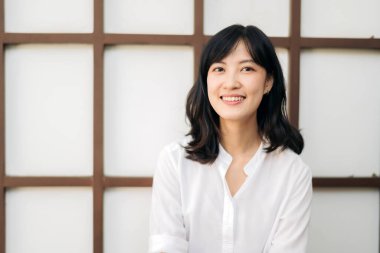 Portrait beautiful young asian woman happiness sitting on wooden grid wall, Happy female is smiling on wooden grid wall