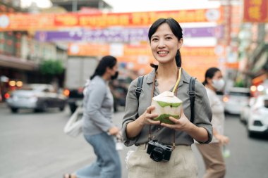 Bangkok, Tayland 'da Çin mahallesindeki bir markette hindistan cevizi suyu içen mutlu genç Asyalı kadın gezgin..