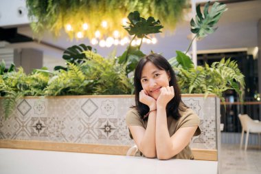 Smiling beautiful asian woman sitting in cafeteria at a shopping mall.