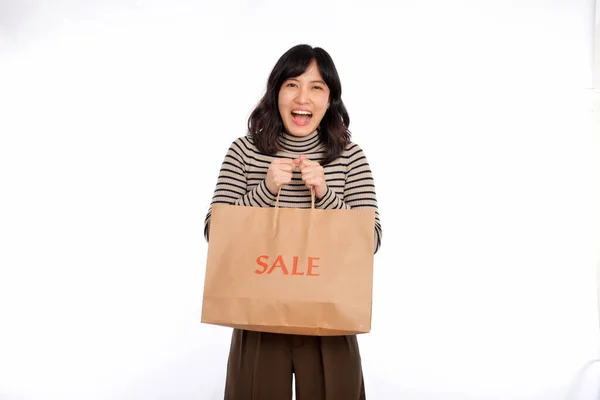 白い背景に幸せな若いアジアの女性カジュアルな制服を保持ショッピングペーパーバッグ ショッピング割引のコンセプト — ストック写真