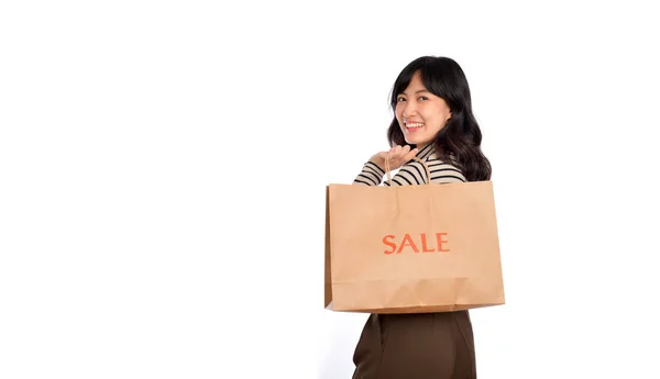 白い背景に幸せな若いアジアの女性カジュアルな制服を保持ショッピングペーパーバッグ ショッピング割引のコンセプト — ストック写真