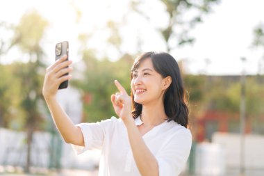 Portrait beautiful young asian woman with smart mobile phone around outdoor nature view in sunny summer day