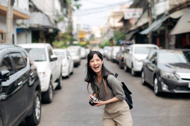 Young Asian woman backpack traveler using digital compact camera, enjoying street cultural local place and smile.