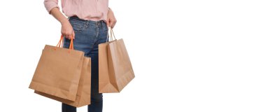 Kadın elinin, beyaz arka planda izole edilmiş günlük kıyafetlerle, kağıt poşet tutarken yakın çekimi. Ekolojik alışveriş paketleme kavramı.