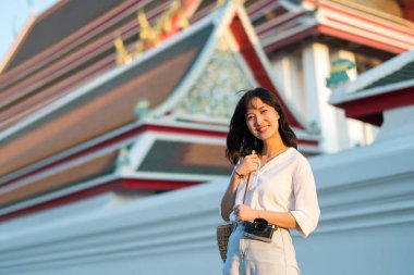 Portrait of young beautiful woman with camera explore street in Bangkok, Thailand