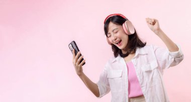 Mutlu gülümseyen Asyalı genç kadın gözlerini kapat ve akıllı telefonla dans et, kablosuz kulaklıkla müzik dinle. Halk duyguları, yaşam tarzı eğlence ve güzellik konsepti.