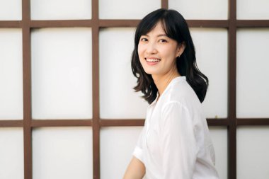Portrait beautiful young asian woman happiness sitting on wooden grid wall, Happy female is smiling on wooden grid wall