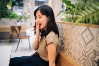 Bir alışveriş merkezindeki kafeteryada oturan güzel Asyalı kadın..