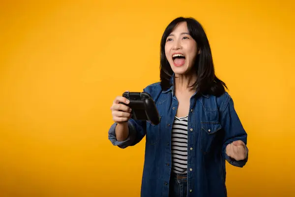 ジョイスティックコントローラを保持し ビデオゲームをプレイデニム服を着て幸せな成功笑顔を持つ肖像アジアの若い女性 趣味のエンターテイメントライフスタイルのコンセプトを楽しくリラックス — ストック写真