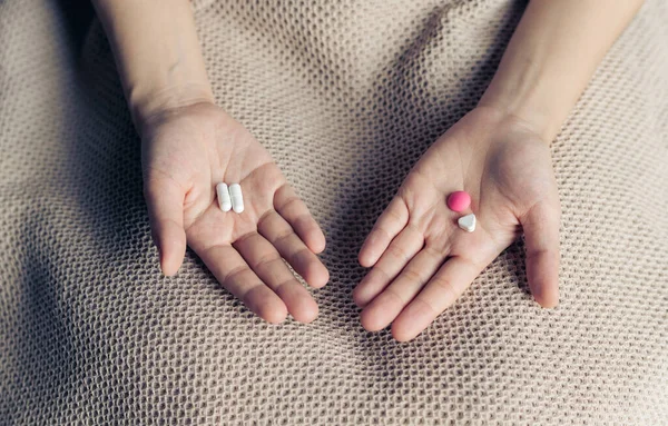 女性の手を保持し 選択のための2つの選択薬薬カプセルを提供しています 白とピンクのキャンディーや薬から選択するのと比較してください 概念優柔不断な意思決定 — ストック写真