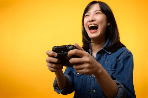 ジョイスティックコントローラを保持し ビデオゲームをプレイデニム服を着て幸せな成功笑顔を持つ肖像アジアの若い女性 趣味のエンターテイメントライフスタイルのコンセプトを楽しくリラックス — ストック写真