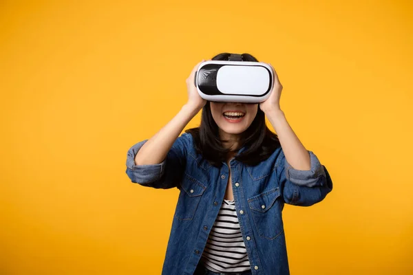 stock image Asian young woman happy success wearing virtual reality headset game entertainment isolated on yellow background. Winner of cyber future video game concept.