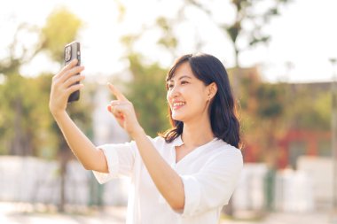Portrait beautiful young asian woman with smart mobile phone around outdoor nature view in sunny summer day