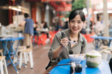 Mutlu genç Asyalı kadın sırt çantası gezgini Bangkok, Tayland 'daki Çin şehir marketinde sokak yemekleri yiyor..