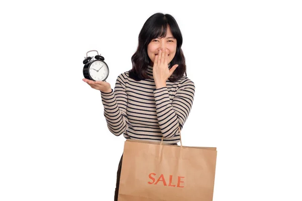 白い背景に目覚まし時計とショッピングペーパーバッグを保持セーターシャツと興奮した若いアジアの女性の肖像画 最後の取引はショッピングのコンセプト — ストック写真