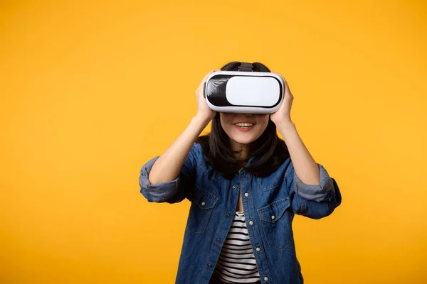 stock image Asian young woman happy success wearing virtual reality headset game entertainment isolated on yellow background. Winner of cyber future video game concept.